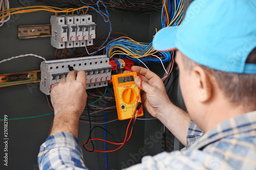Mature electrician measurin...