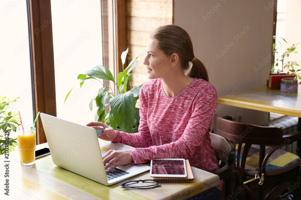 Young freelancer with laptop working in cafe Young freelancer with laptop working in cafe