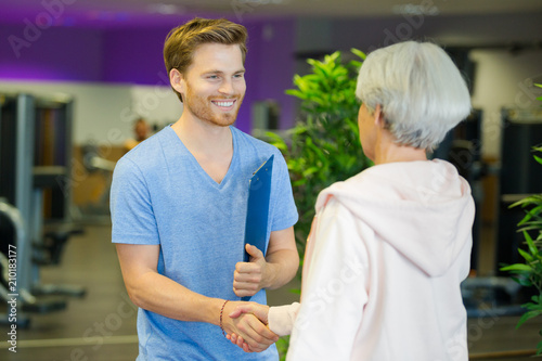 personal trainer and elderly fit woman shaking hands