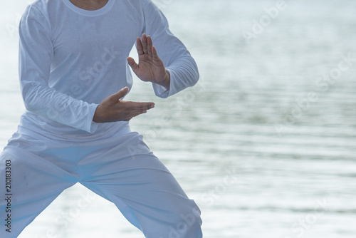 Young man practicing traditional Tai Chi Chuan, Tai Ji and Qi gong in the park for healthy, traditional chinese martial arts concept. photo