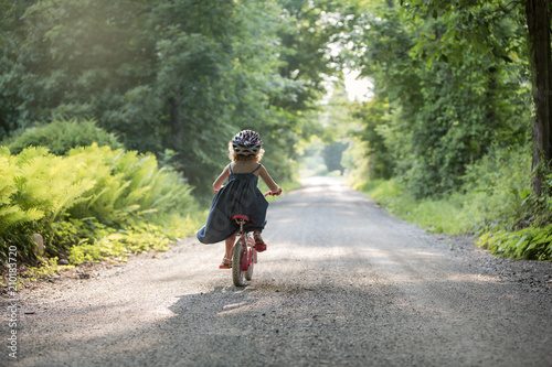 Little Girl Racing down road alone on bicycle