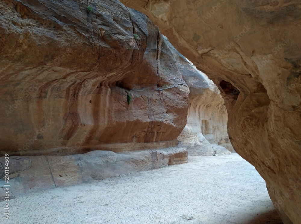 The fantastic narrow passage with high sandstone curve walls. There is in Jordan, near the ancient city Petra. The weather is sunny and hot.