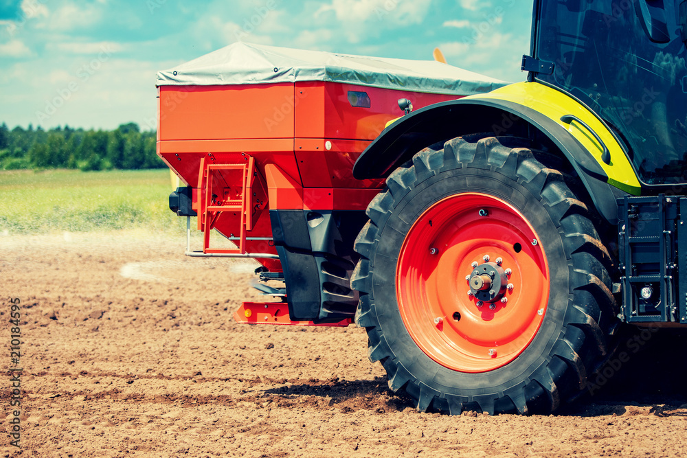 Fototapeta premium tractor fertilize the field with granular fertilizer