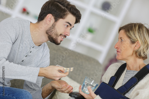 young man giving pills to an ill woman