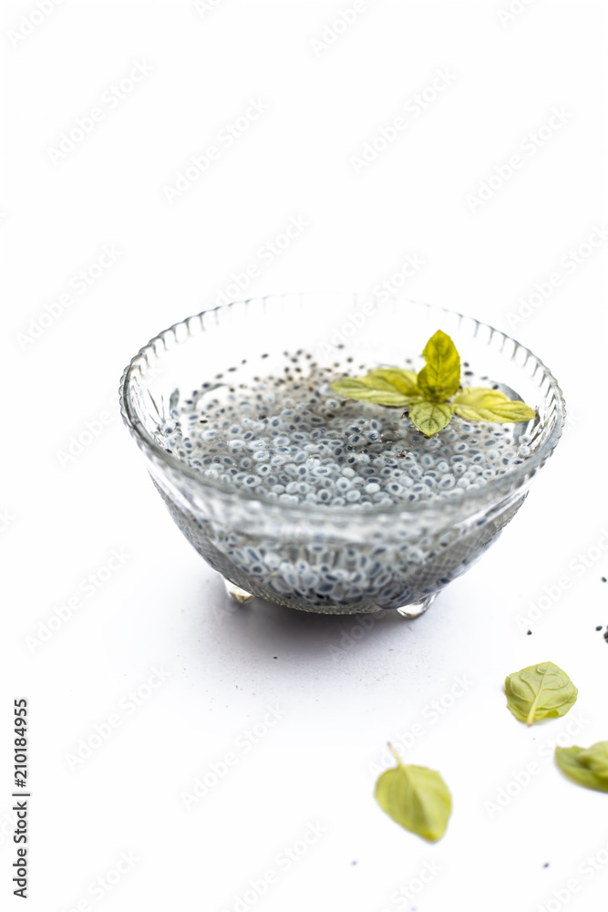 Soaked sweet basil or tukhmaria or falooda seeds or sabja seeds in a bowl with raw sweet basil seed isolated on white with a mint leaf. Soaked sweet basil or tukhmaria or falooda seeds or sabja seeds in a bowl with raw sweet basil seed isolated on white with a mint leaf.