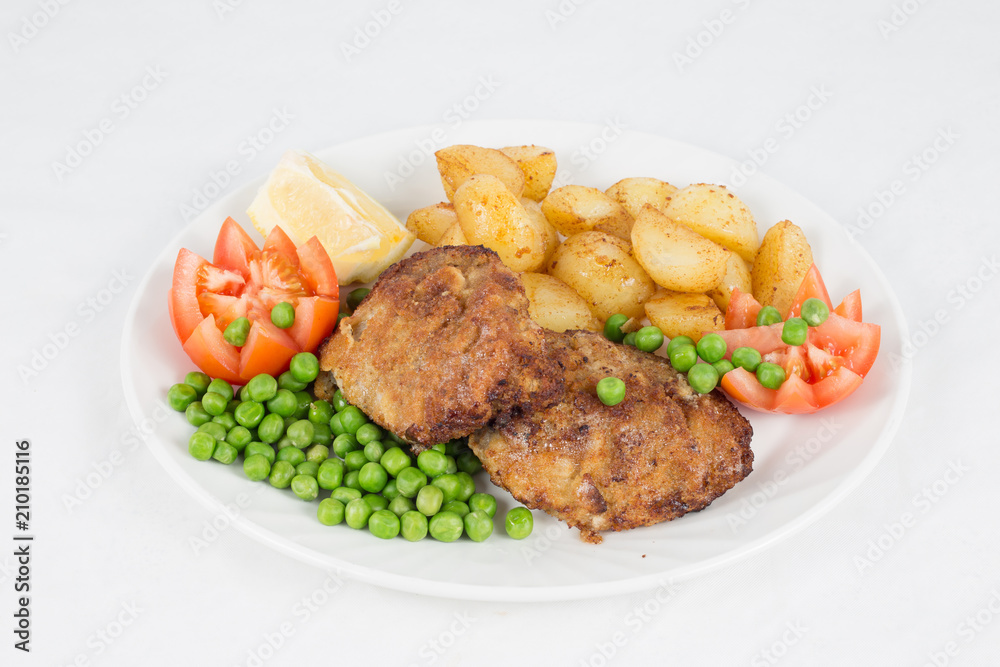Fried Beef Steak Served With Fried Potatoes, Tomatoes, Peas And Slices Of Lemon On White Plate