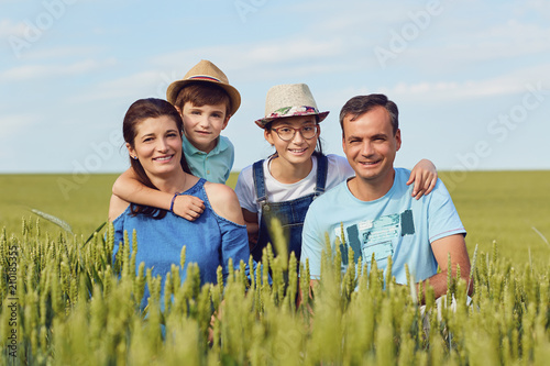 Portrait of a happy family sitting on nature in the grass in summer.