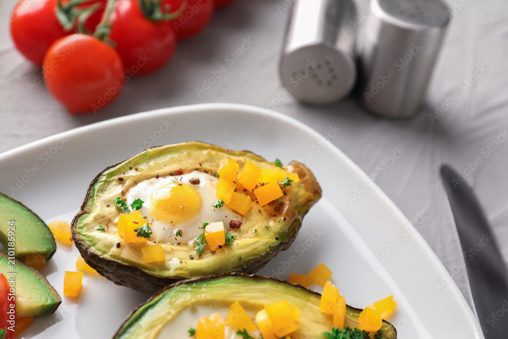 Baked avocado with eggs on plate, closeup