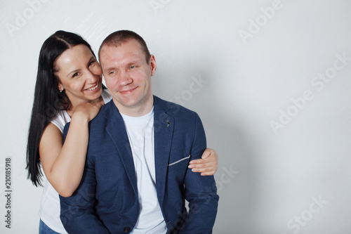 Picture of happy young loving couple standing over grey wall.