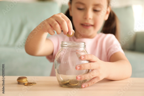 Little girl putting coins i...