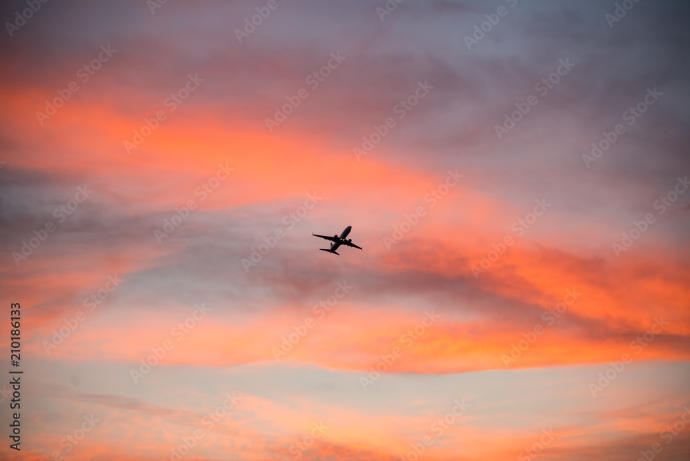 Commercial airline silhouetted against colorful sunset sky