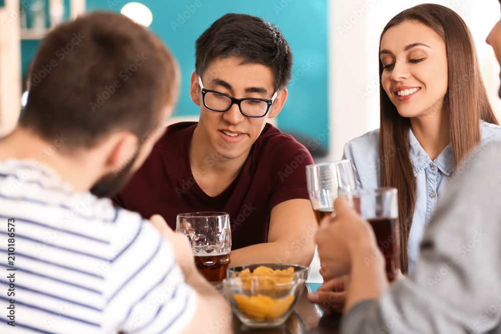 Group of cheerful friends drinking beer in bar