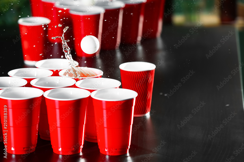 Cups and plastic ball for beer pong game on table Photos