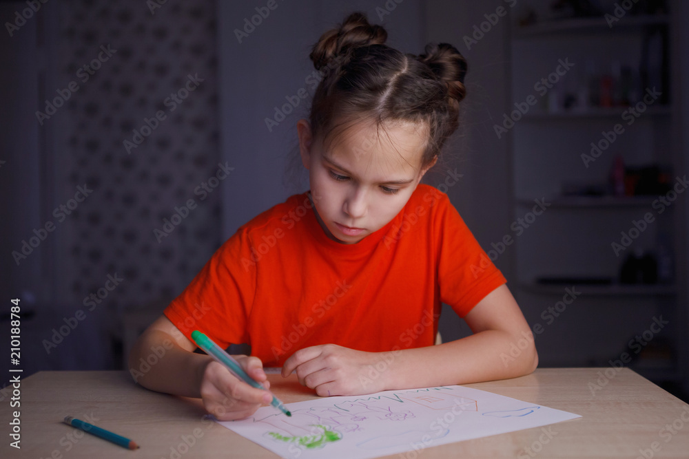 little girl draws a marker while sitting at the table at home little girl draws a marker while sitting at the table at home