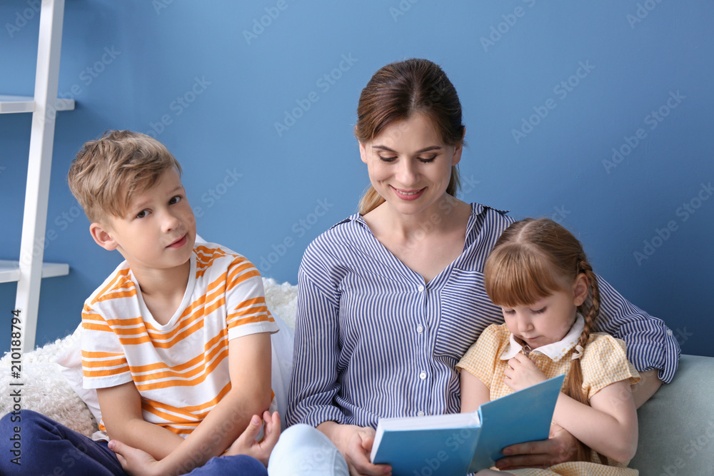Mother and her children reading book together at home Mother and her children reading book together at home