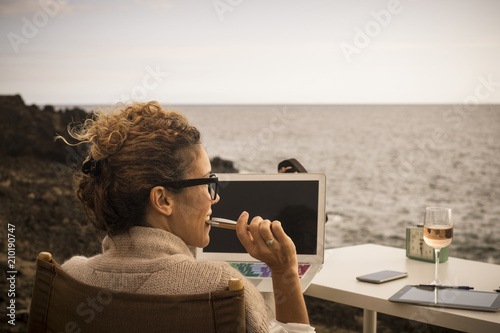 Nice lifestyla for nbeautiful caucasian woman working in alternative office place. outdoor in front of the ocean. digital nomad and internet work for modern possibilities and freedom from closed photo