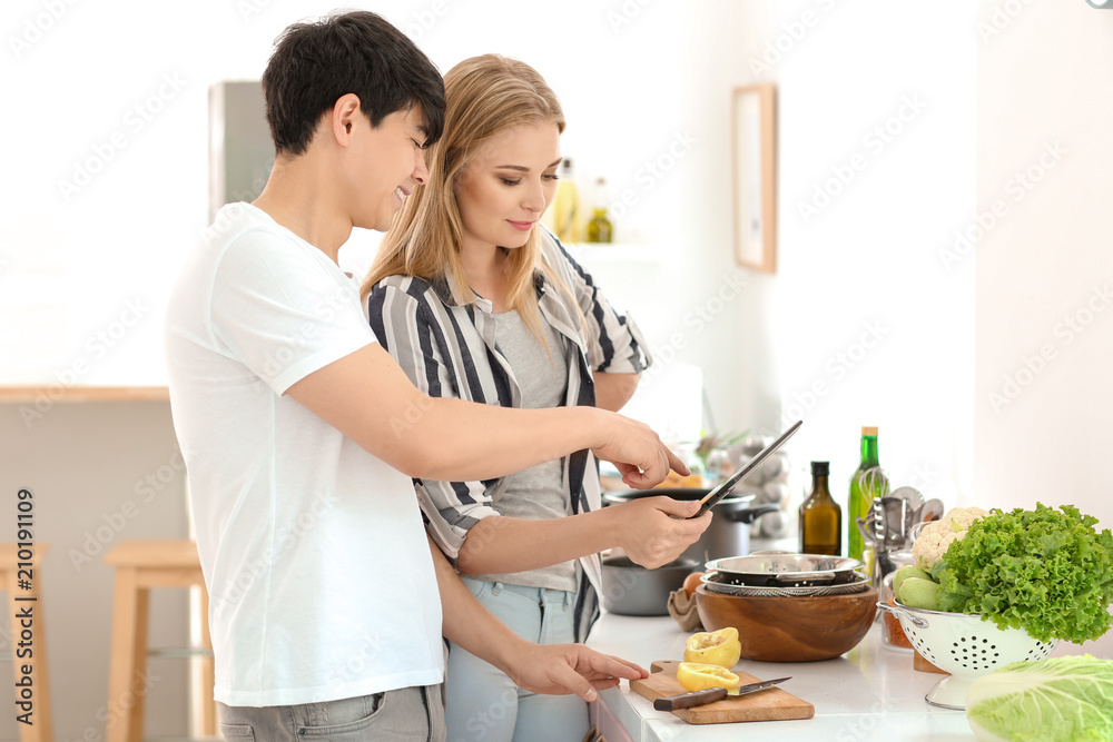 Friends with tablet PC reading recipes in kitchen Friends with tablet PC reading recipes in kitchen