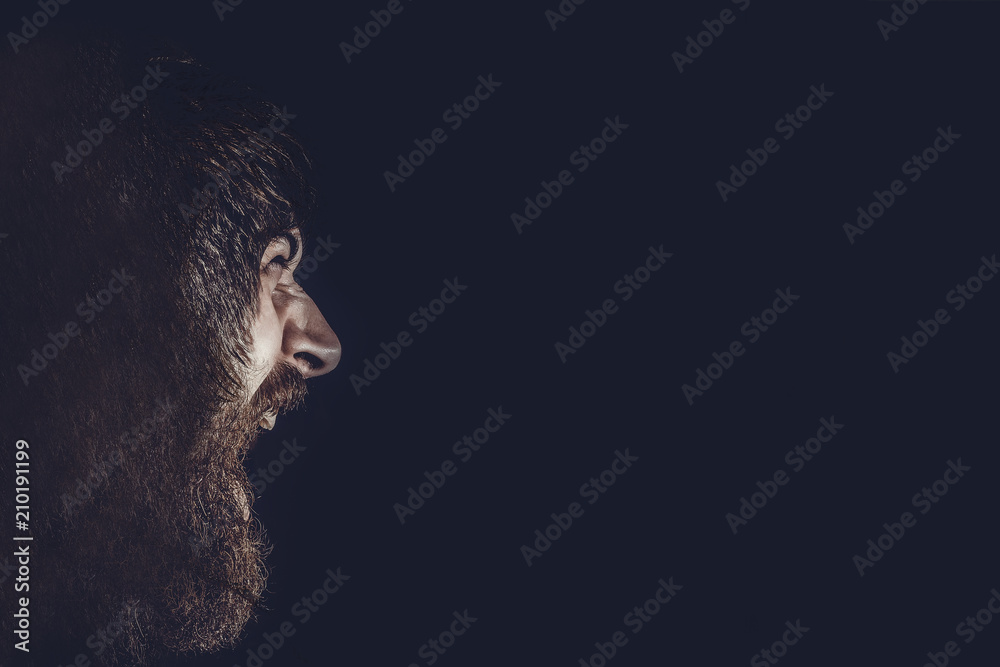 Overgrown man aggressively screams a photo in profile on a black background, toned image Overgrown man aggressively screams a photo in profile on a black background, toned image