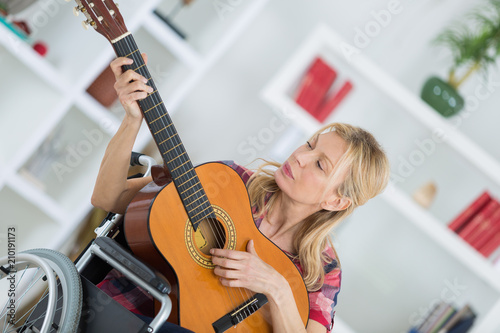portrait of young lady in wheelchair playing guitar © auremar