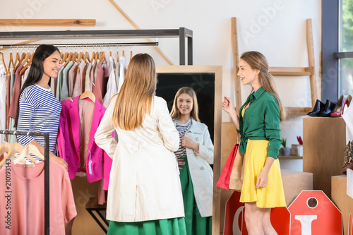 Young beautiful women choosing clothes in modern shop
