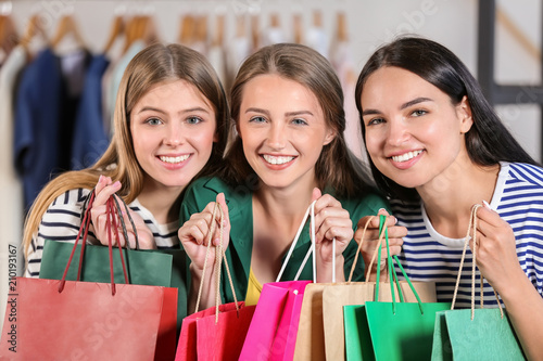 Young beautiful girls with shopping bags in clothing shop