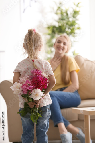 Cute little girl hiding bouquet of flowers for mother behind her back