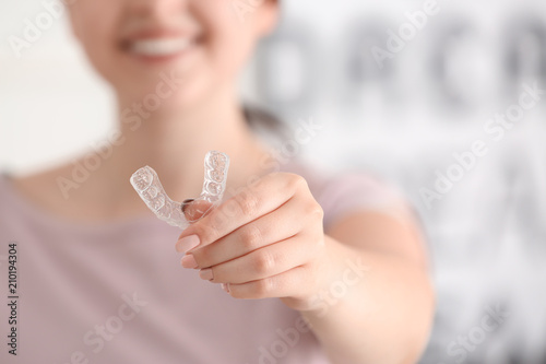 Woman holding occlusal splint on light background, closeup photo