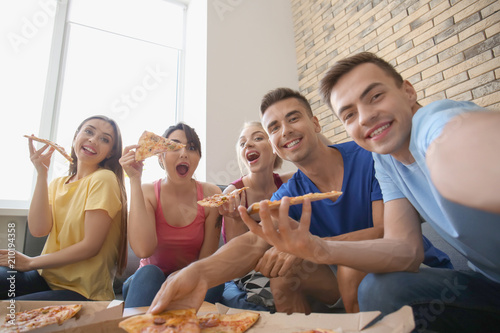 Young people taking selfie with delicious pizza at home party