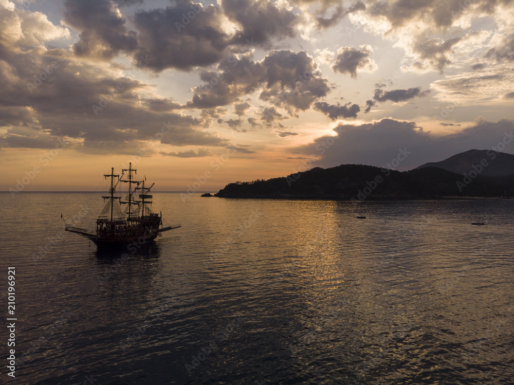 Aerial view looking out at a pirate ship at sunset with dramatic sky, Oludeniz, Turkey