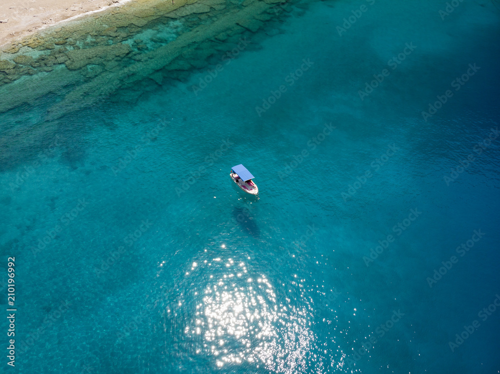 Aerial over a small fishing boat in turquoise water on a bright day in Oludeniz, Turkey
