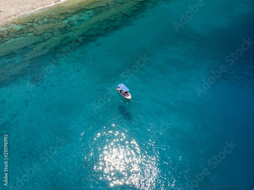 Aerial over a small fishing boat in turquoise water on a bright day in Oludeniz, Turkey