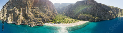 Remote beach from the air surrounded by a steep sided valley and turquoise water with sailing ship, Oludeniz, Turkey panoramic