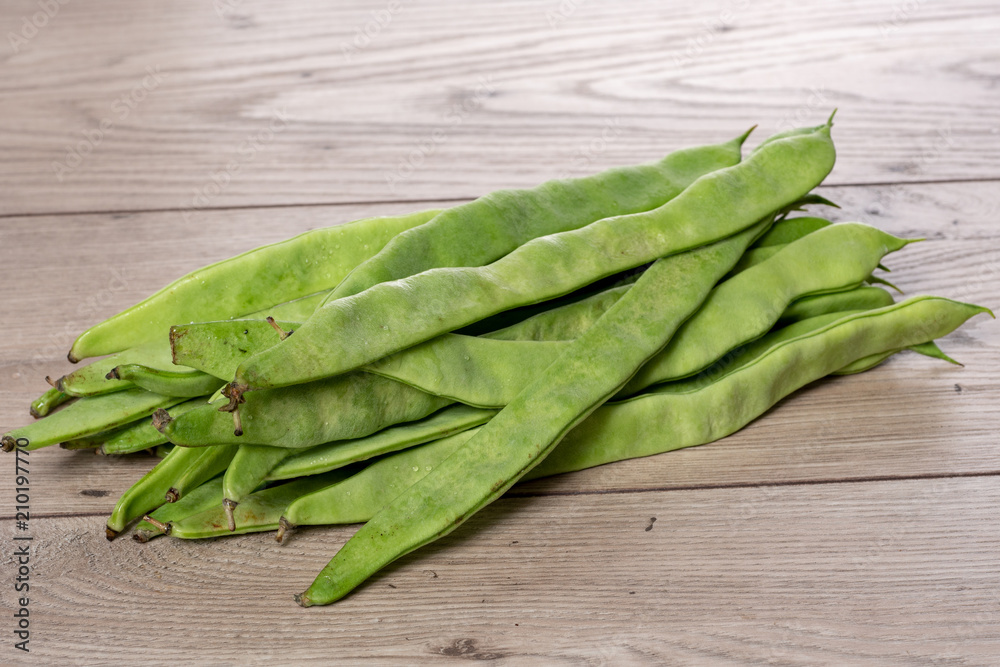 bunch of flat beans on a wooden board. bunch of flat beans on a wooden board.