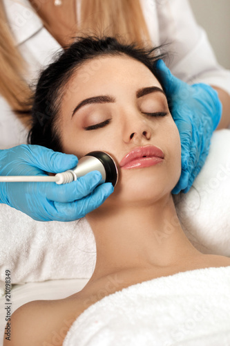 Beautician makes cleaning of face in spa salon.