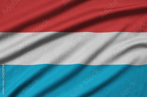 Luxembourg flag  is depicted on a sports cloth fabric with many folds. Sport team banner photo