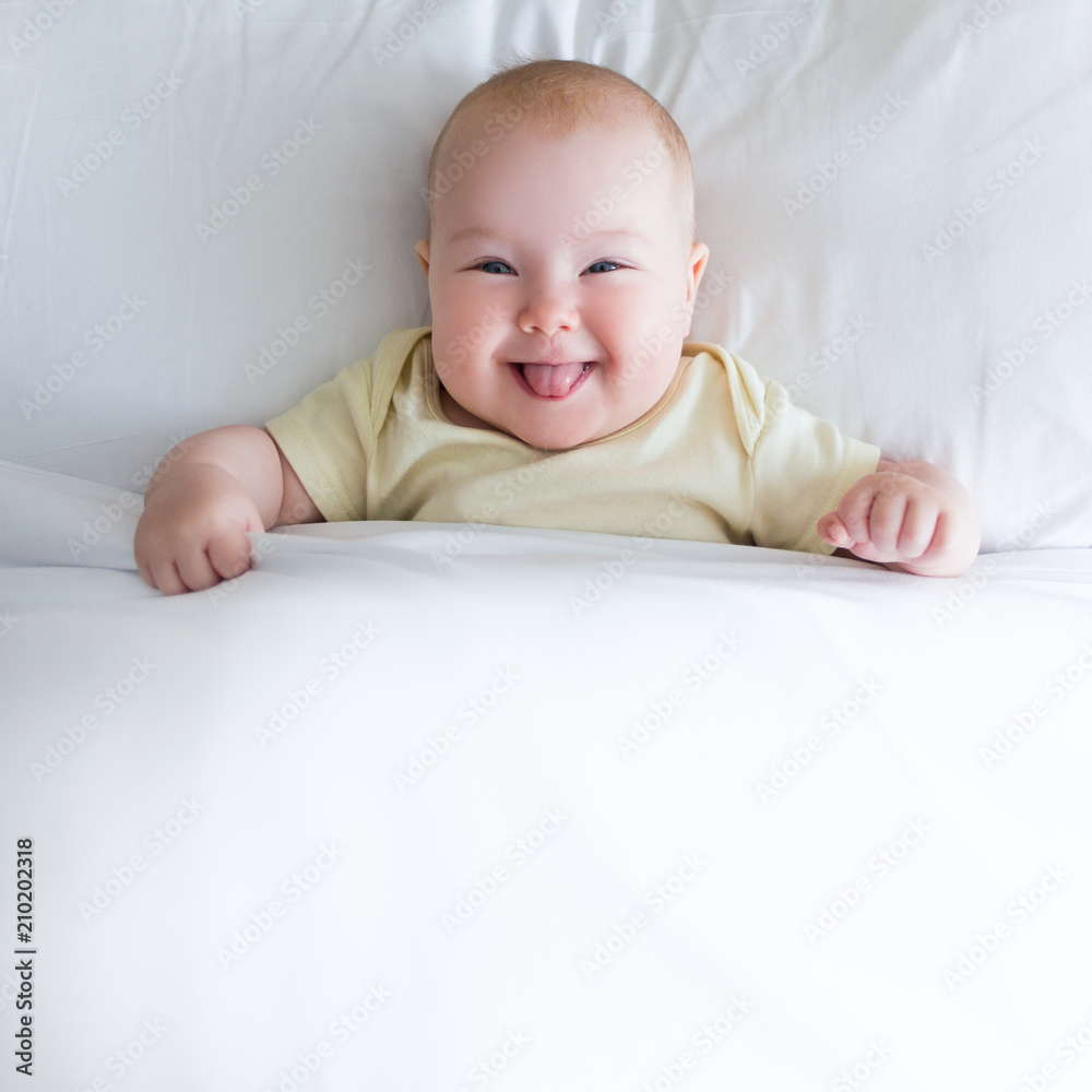 top view of funny little baby lying on the bed under white blanket top view of funny little baby lying on the bed under white blanket
