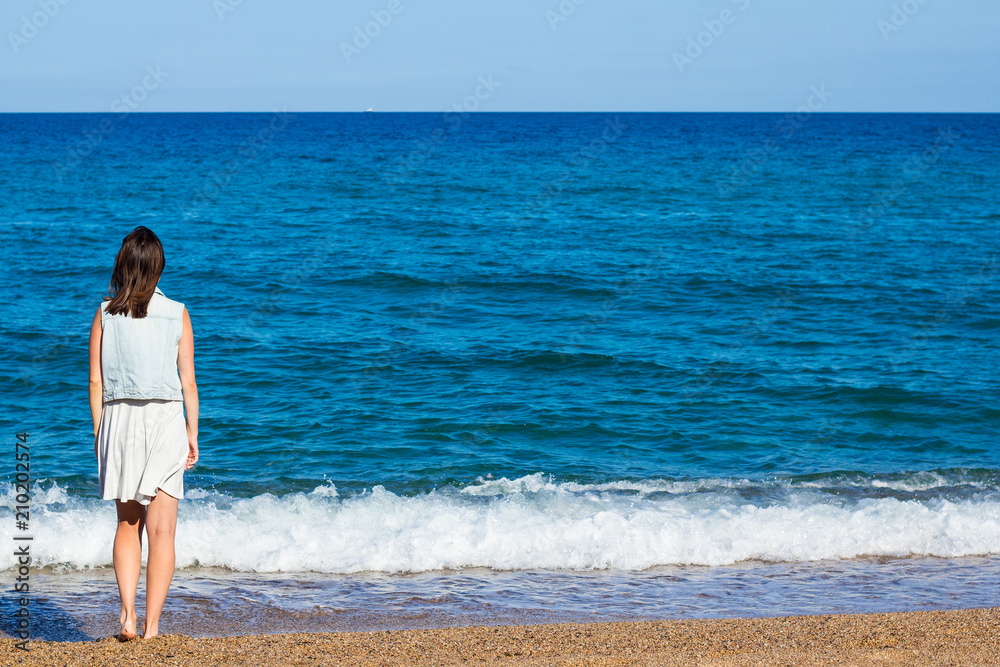 summer and travel concept - young woman looking at the sea