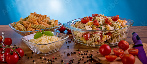 Delicious pasta salad or Mediterranean salad. Tomatoes mozzarella basil corn spice and olive oil on a wooden table. Traditional Italian food