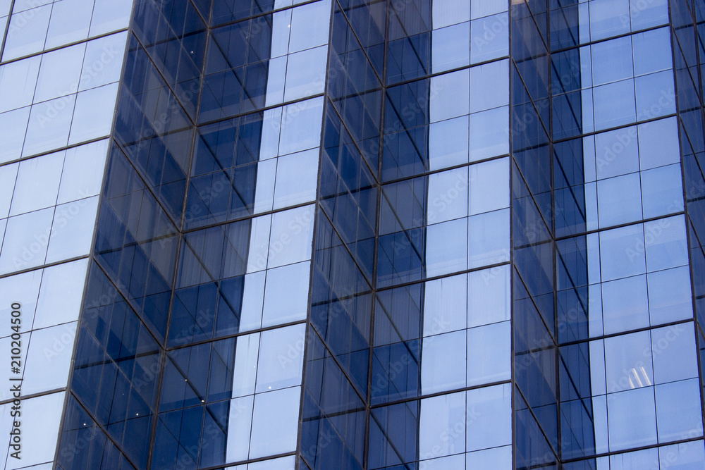 Obraz premium A glass window wall of an office building with several corners. The light and the position of the window walls generate a contrast effect.