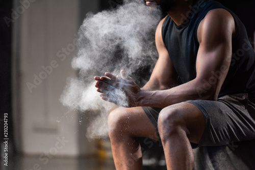 cropped shot of muscular african american sportsman applying talcum powder on hands
