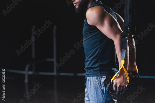 side view of muscular african american sportsman exercising with resistance bands