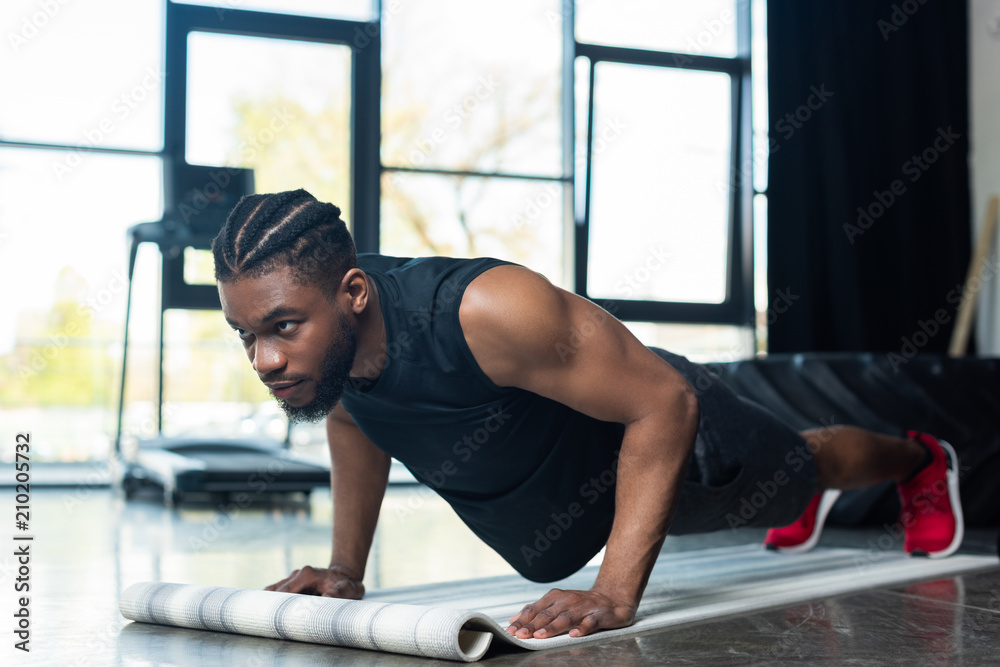 muscular african american sportsman doing push ups and looking away in gym muscular african american sportsman doing push ups and looking away in gym