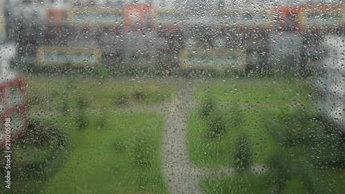 Raindrops rolling down a window on a rainy cloudy day in a residential apartment district, Prague 
