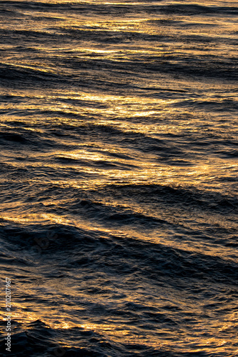 Golden sunset reflecting on ocean waves 