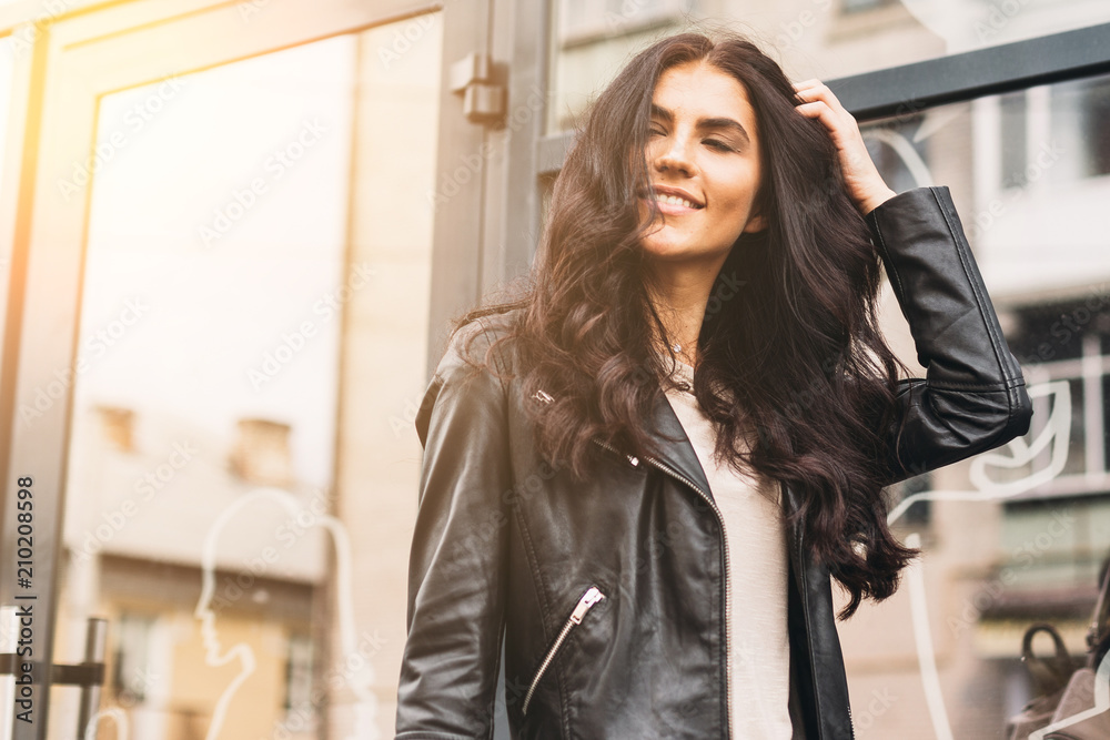 Young pretty latin woman walking near shops in city centre