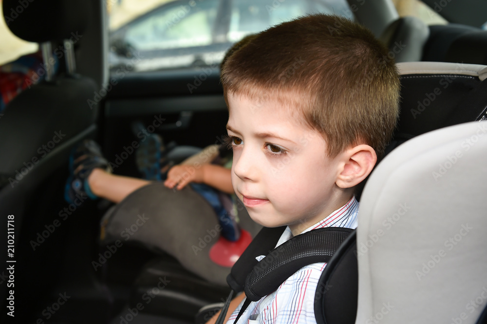 child boy sitting in child seat in a car