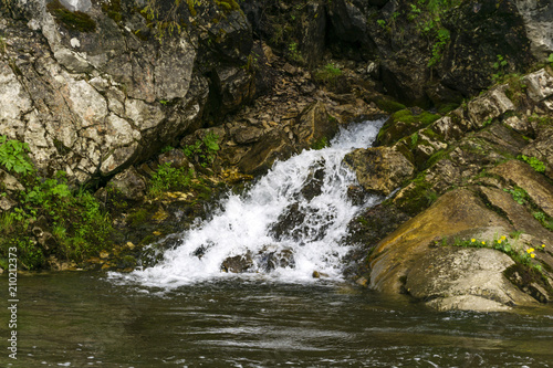 The spring follows a waterfall from the rock and flows into the river on a precipitous river bank