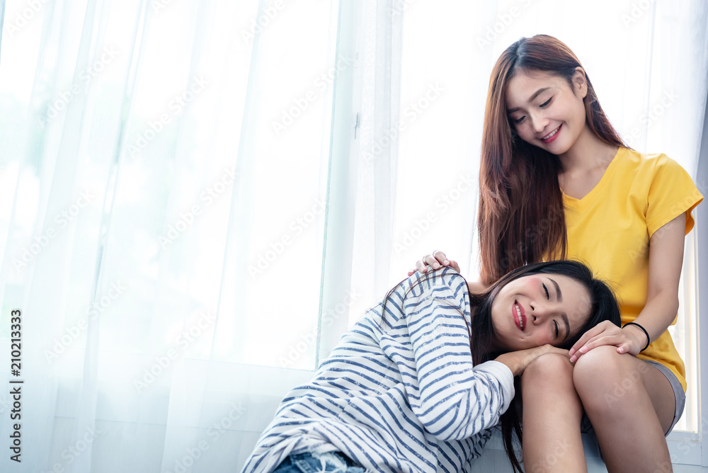 Asian couple take care together near white window with soft sunshine in happiness moment together. People and Lifestyles concept. Lesbian and friendships theme. LGBT theme. Asian couple take care together near white window with soft sunshine in happiness moment together. People and Lifestyles concept. Lesbian and friendships theme. LGBT theme.