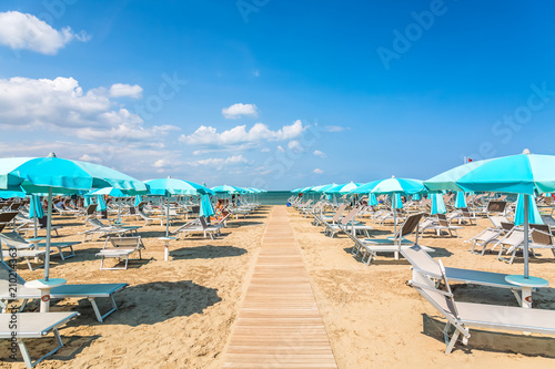 Beach chairs and umbrellas in Rimini, Italy during summer day with blue sky. Summer vacation and relax concept. photo