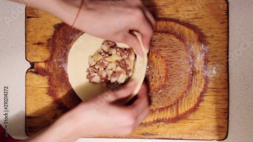 Women prepare vak belyash - national homemade meat pies. Traditional russian meat pies belyashi. belyashes on a on wood chopping board. Russian, Bashkir and Tatar cuisine. Top view. photo